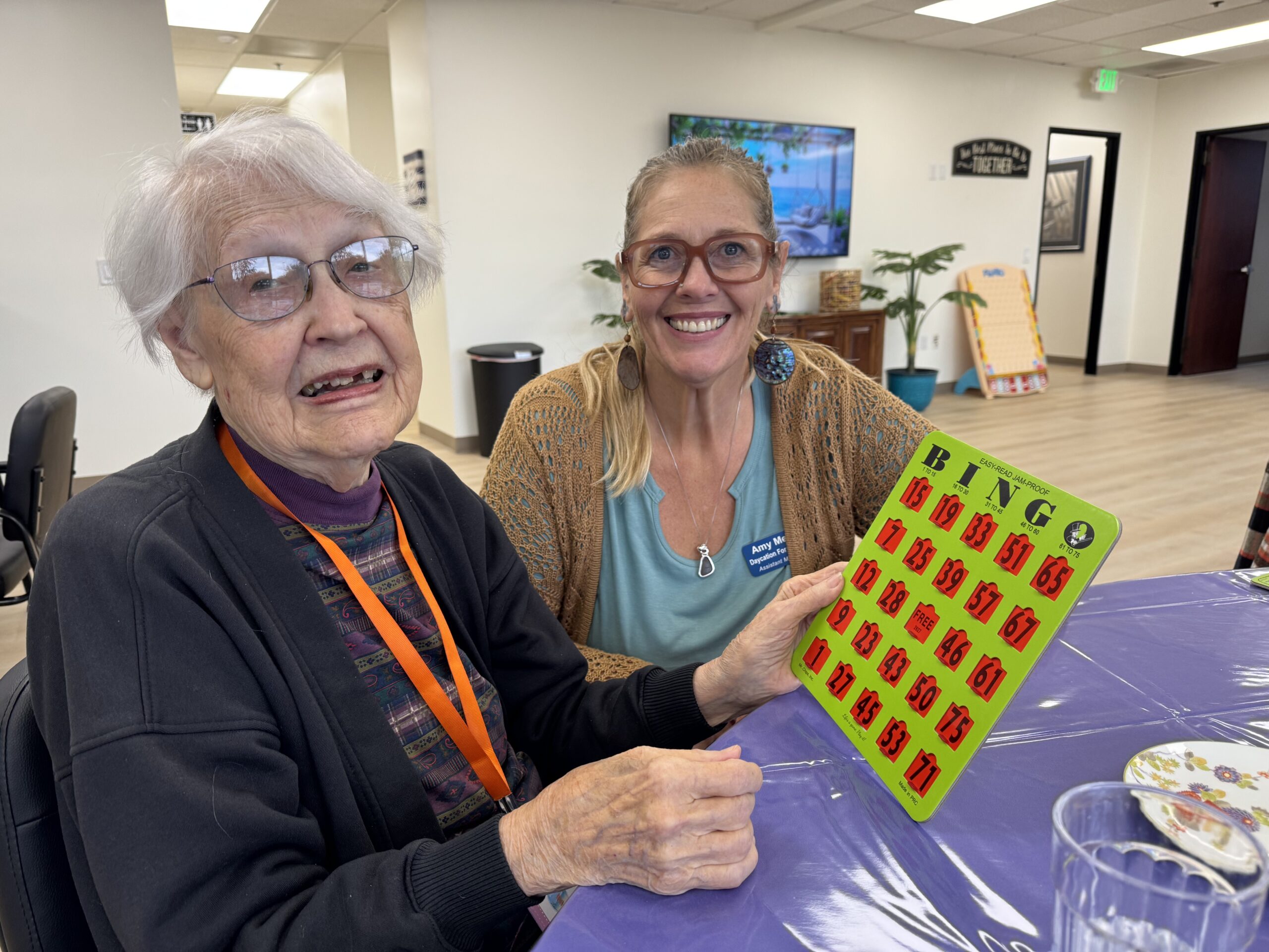 A participant and staff member holding up a bingo card at Daycation for Seniors El Dorado Hills